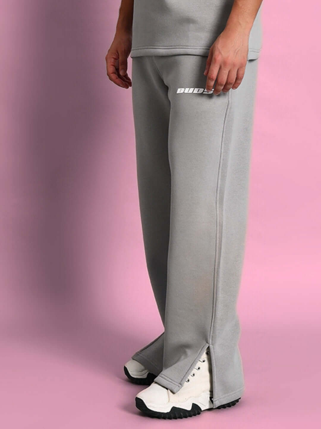 Skoda cotton fleece grey jogger pants with white sneakers on pink background, showcasing comfort and style for casual wear.