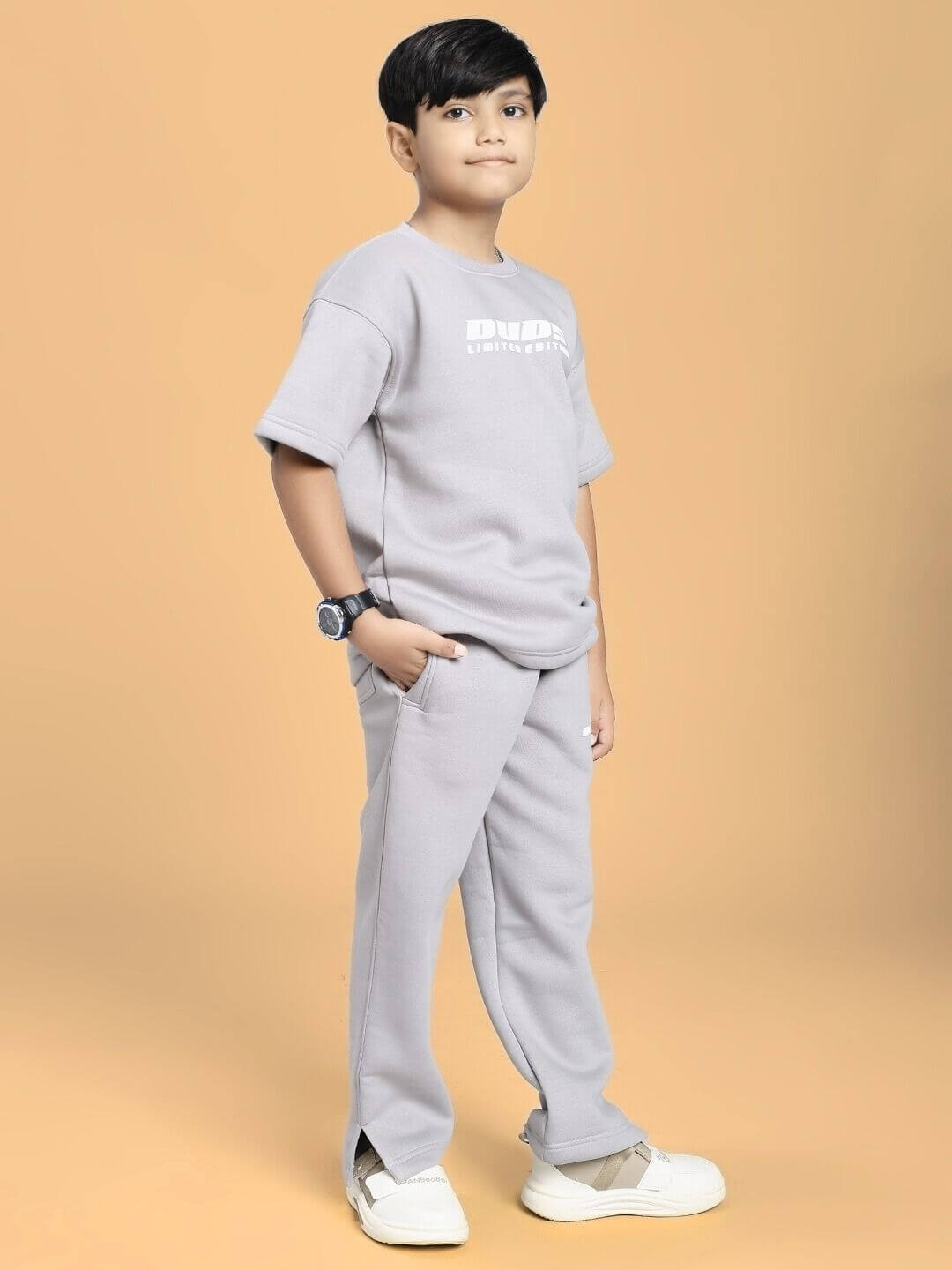 Child wearing SKODA FLEECE CO-ORD FOR BOYS AND GIRLS GREY, standing confidently in grey fleece outfit with watch and sneakers.