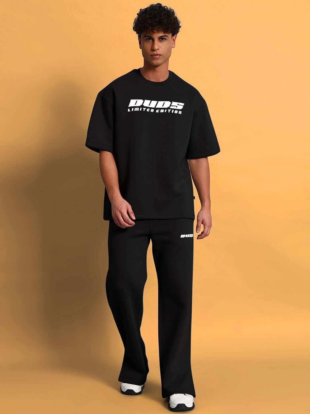 A model wearing SKODA Fleece Co-Ord in black from DUDS, showcasing an oversized top and matching pants against a neutral background.