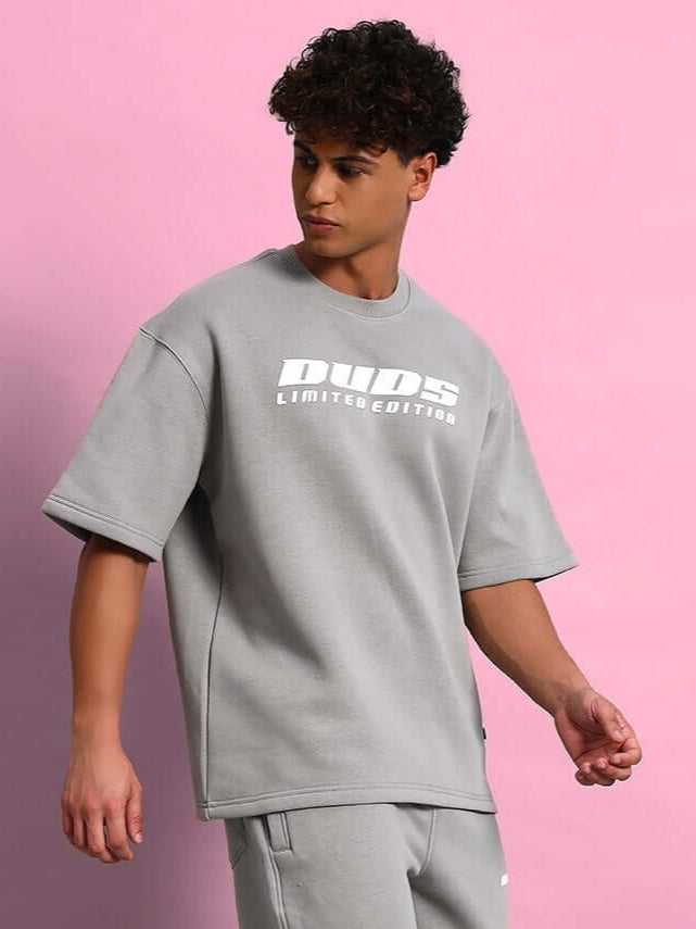 Model wearing SKODA FLEECE OVERSIZED T-SHIRT GREY against pink background.
