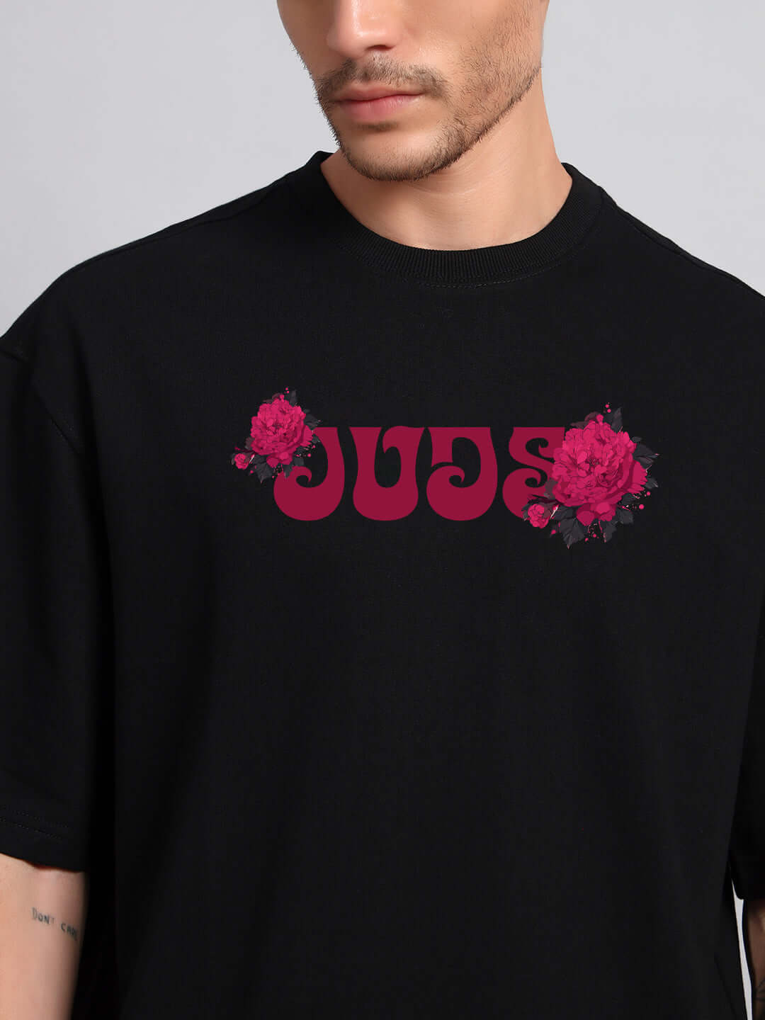 Model wearing SKULL ROSES OVERSIZED T-SHIRT BLACK with rose graphic print.