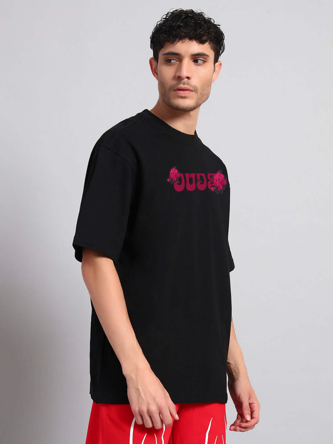 Man wearing SKULL ROSES OVERSIZED T-SHIRT BLACK with a bold skull and roses graphic, showcasing edgy style and relaxed fit.