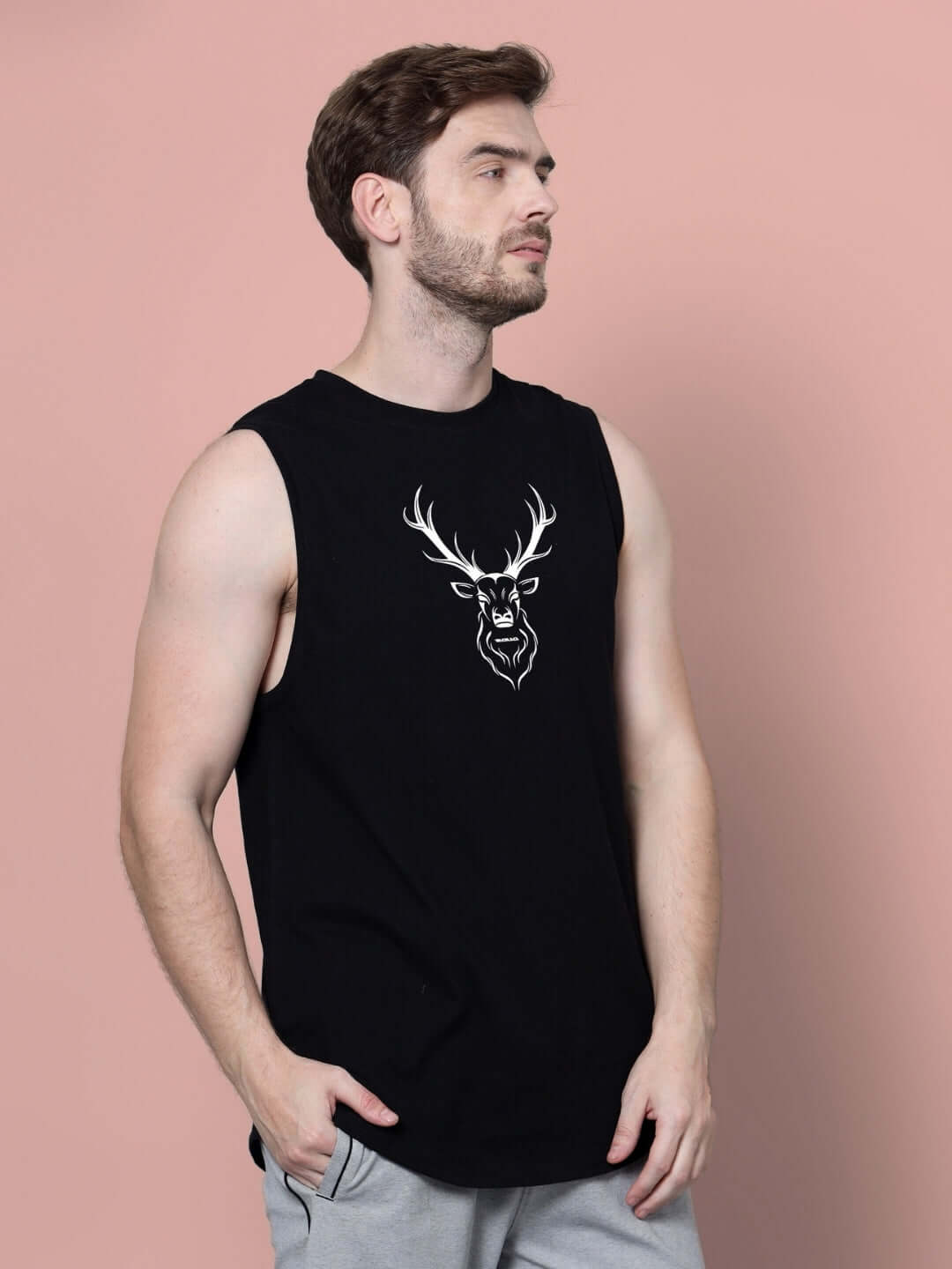 Man wearing a black sleeveless shirt with a white deer graphic on a pink background.