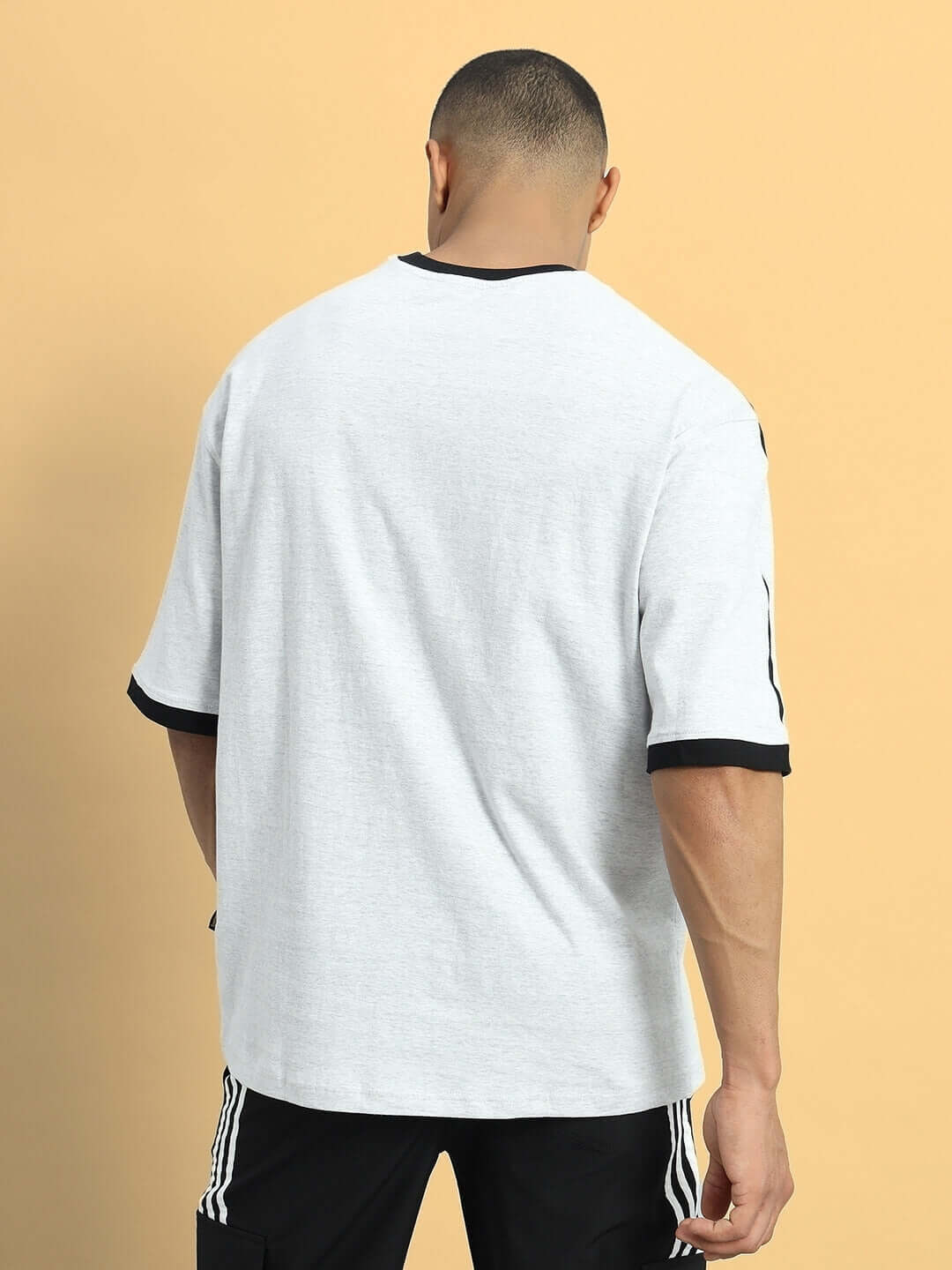 Back view of a male model wearing a grey melange SMASH oversized T-shirt made from premium cotton French terry fabric.