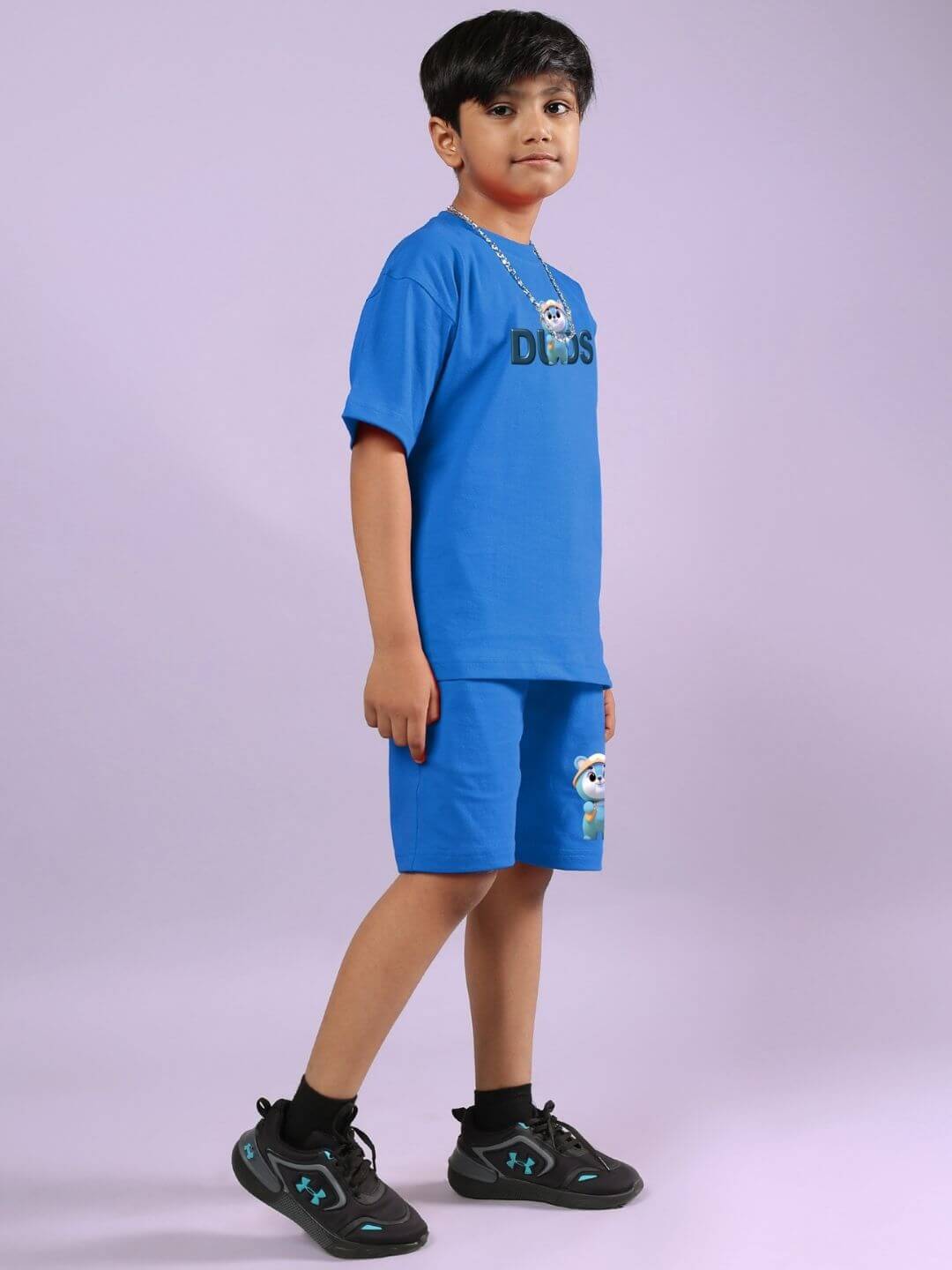 Child wearing SMILEY BEAR CO-ORD FOR BOYS AND GIRLS BLUE set, standing sideways, demonstrating the playful design and fit.
