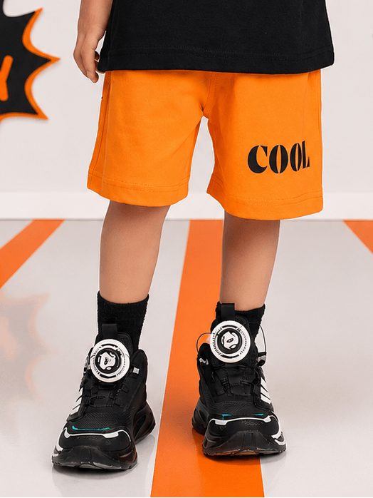 SMILEY EYES COOL SHORTS FOR BOYS GIRLS ORANGE worn with black sporty sneakers on a stylish background.