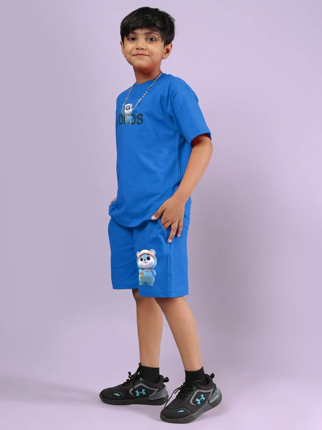 Child wearing SMILEY BEAR CO-ORD FOR BOYS AND GIRLS BLUE, standing against a purple background, showcasing the playful and comfy outfit.