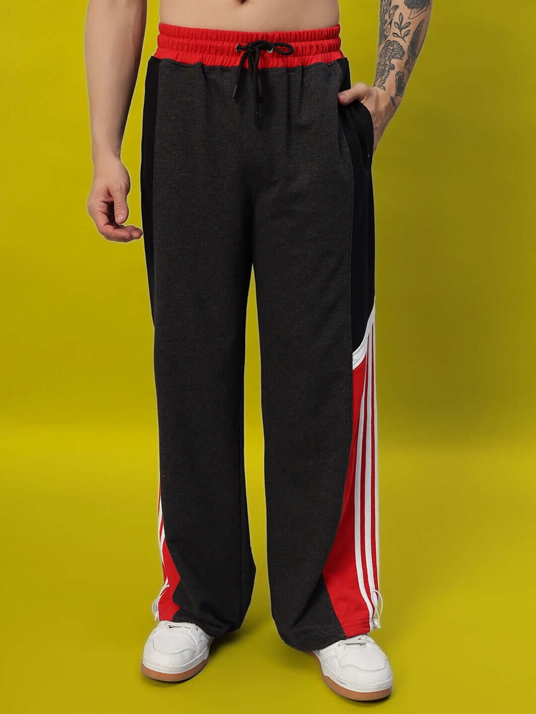 SNICKER relaxed-fit joggers in dark grey and red, customizable fit, made by DUDS tailors, shown against yellow background.