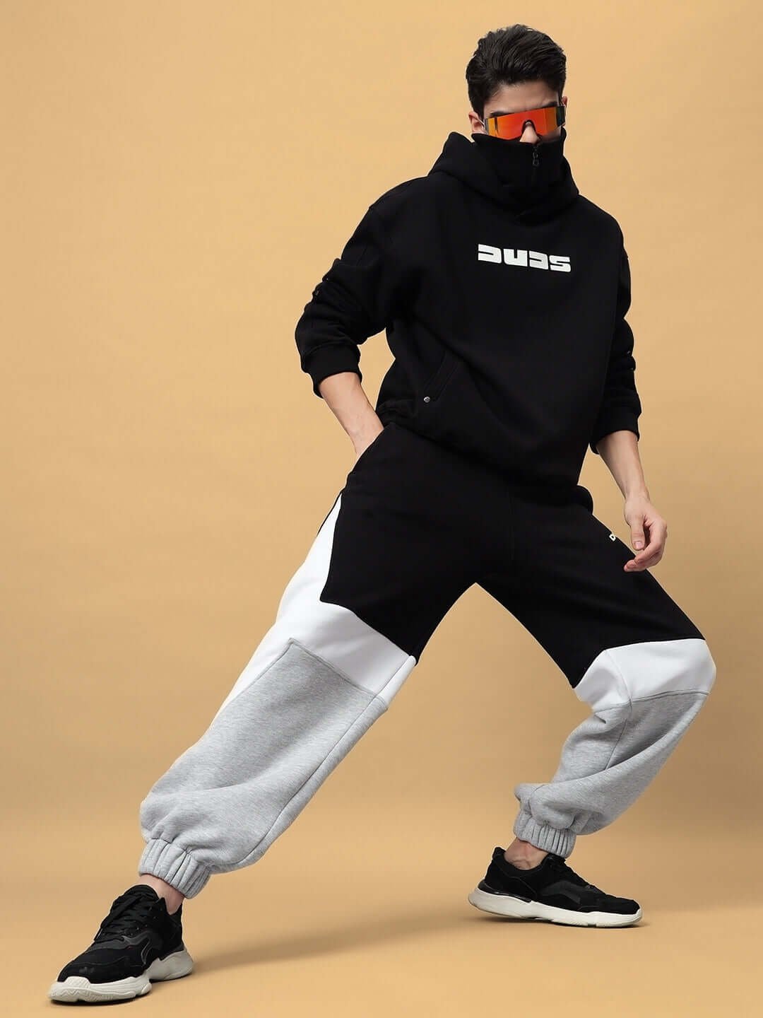 Man wearing SNIPPER COTTON FLEECE HOODIE BLACK with matching streetwear ensemble in dynamic pose.