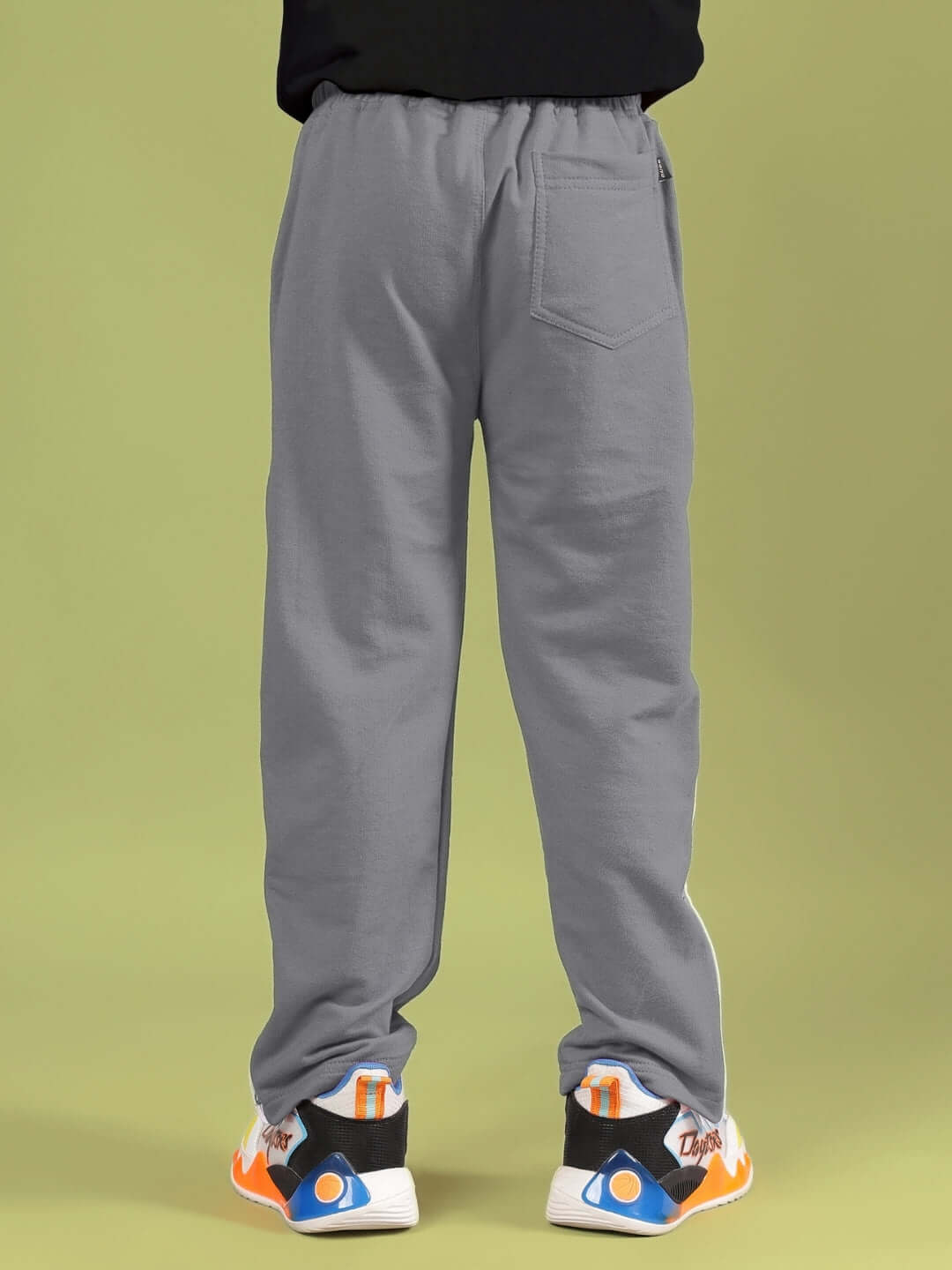 Back view of SNOOPY RIMIX CO-ORD FOR BOYS & GIRLS BLACK GREY showing grey pants and sneakers on green background.