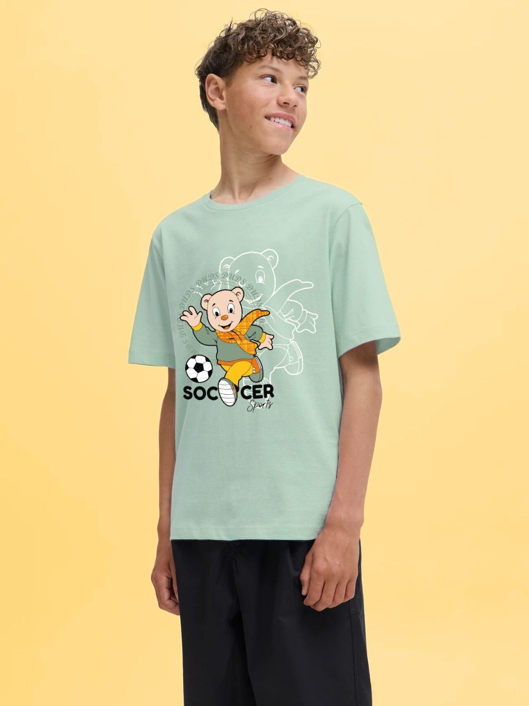 Boy wearing SOCCER PRINTED T-SHIRT FOR BOYS AND GIRLS LIGHT GREEN with playful soccer design on the front, perfect for young sports enthusiasts.