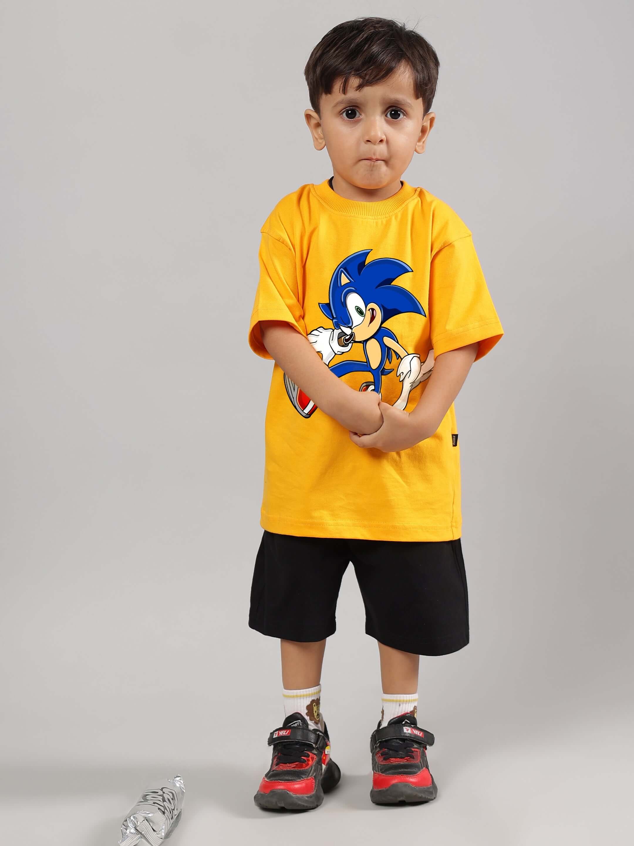 Young child modeling Sonic-themed yellow and black co-ord set for boys and girls, featuring a Sonic graphic tee and black shorts.