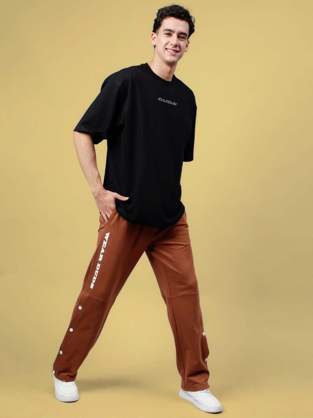 Model wearing a Sonic Sound Reflector oversized black T-shirt made from premium cotton, styled with brown pants against a yellow backdrop.