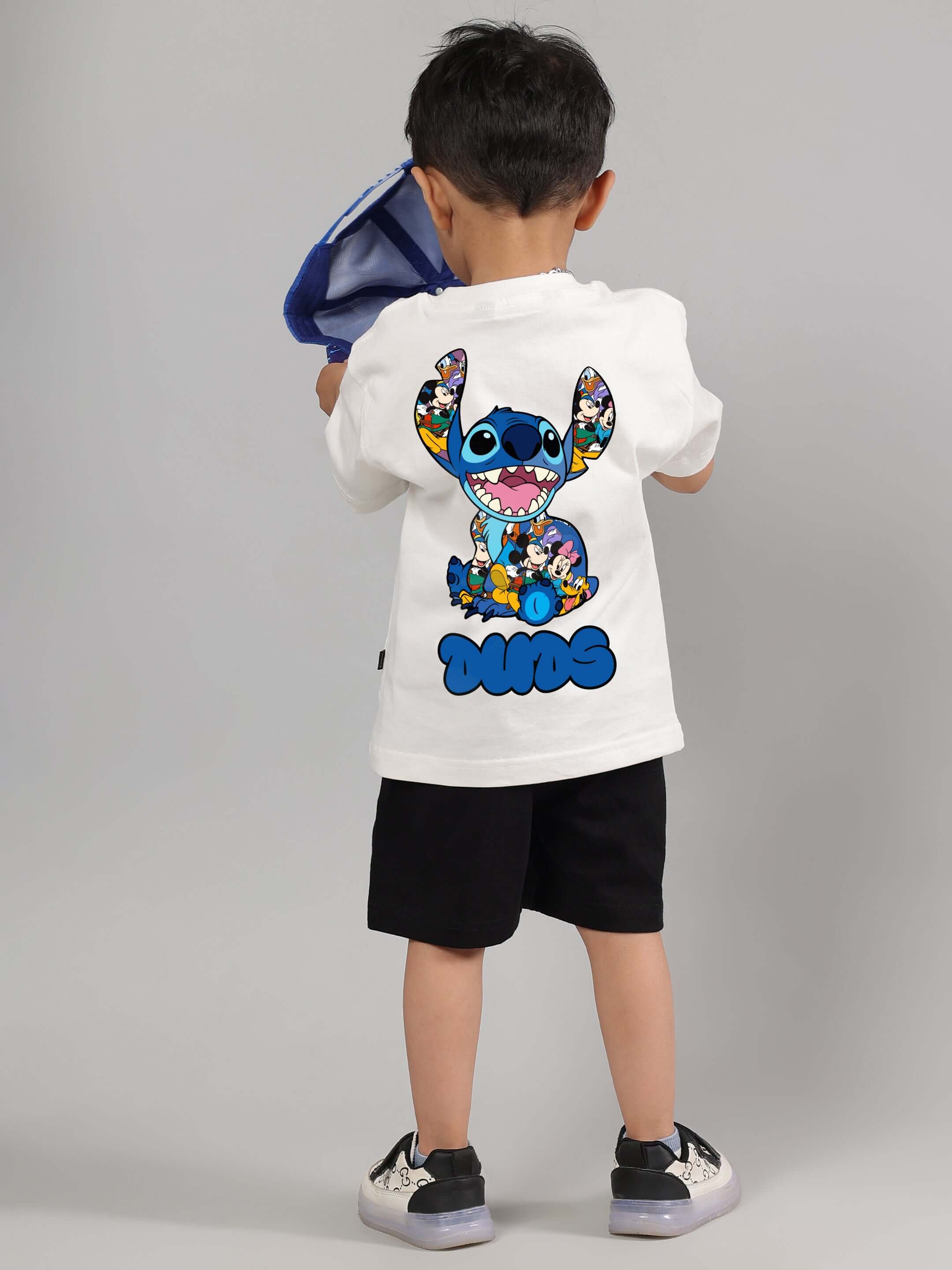 Boy wearing SORE summer co-ord set in off white and black from DUDS, featuring playful graphic design on back of shirt.