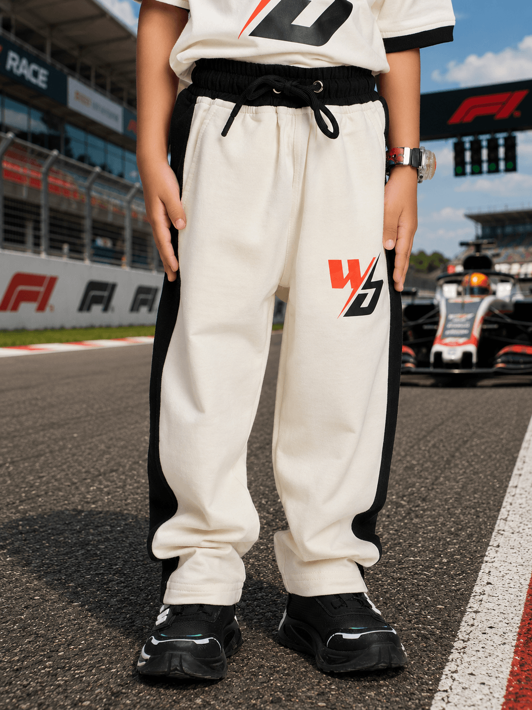 SPEED SURGE CO-ORD SET BOYS GIRLS WHITE BLACK featuring stylish joggers on a racetrack backdrop.