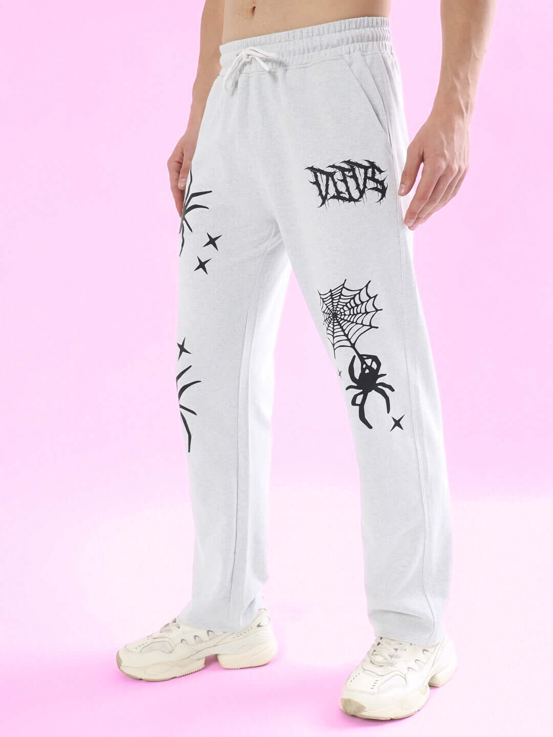 Light grey jogger pants with spider web design and custom fit option, made to order by DUDS. Shown on pink background.