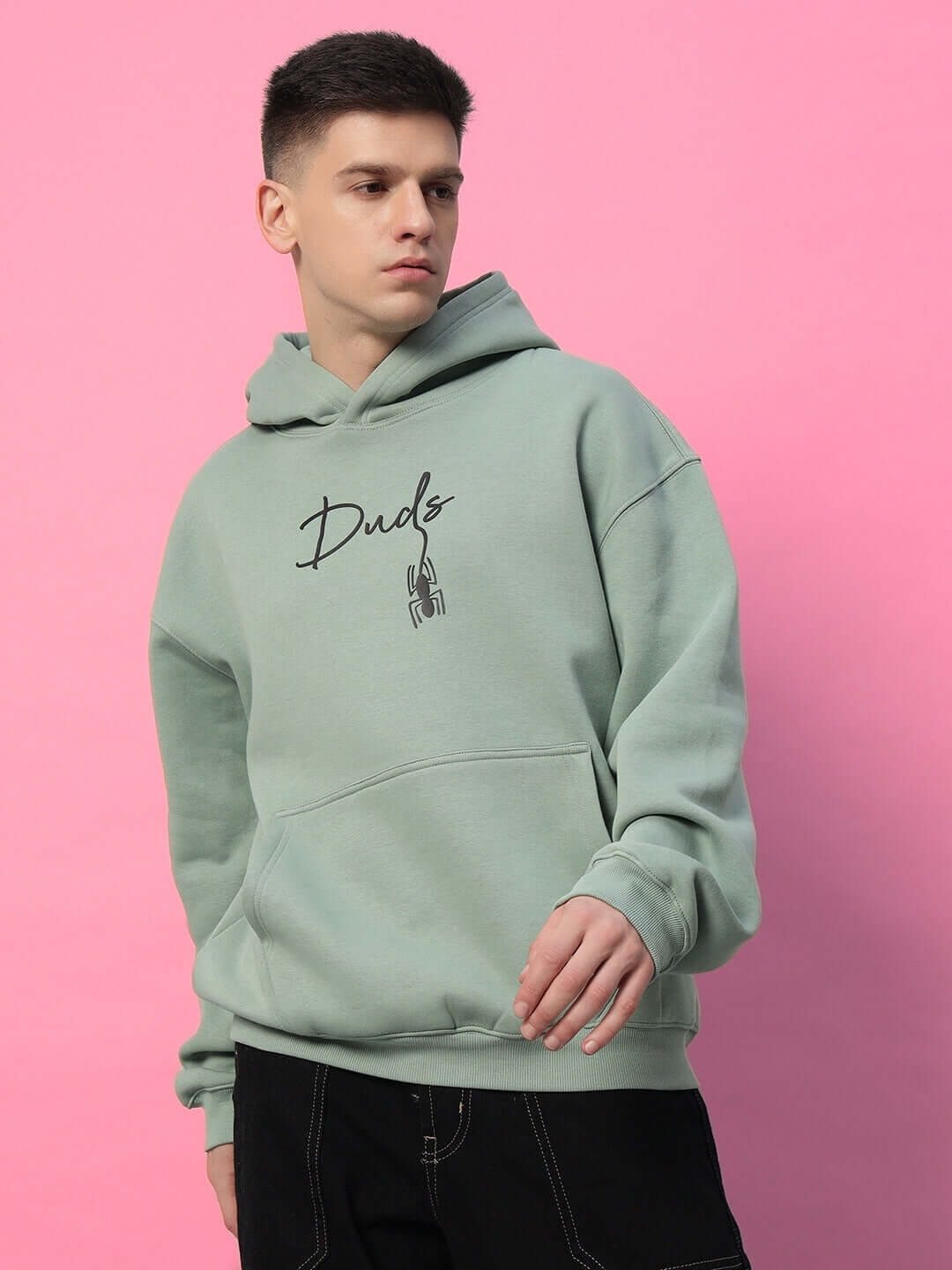 Model wearing Spiderman Oversized Fleece Hoodie Jade Green with vibrant graphic on pink background, showcasing relaxed fit and style.