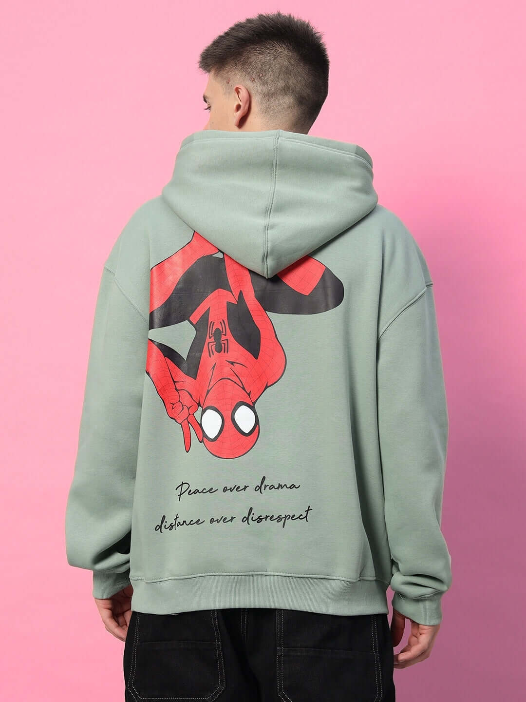 Back view of SPIDERMAN OVERSIZED FLEECE HOODIE JADE GREEN with Spiderman graphic and quote on a pink background.