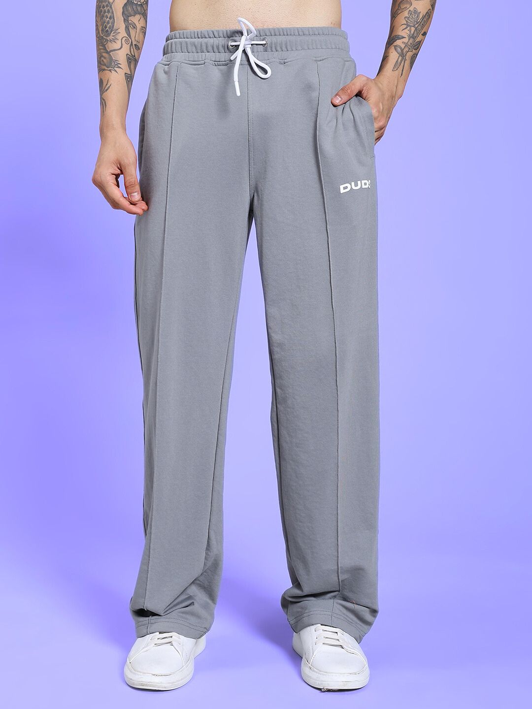 SPIRAL RELAXED-FIT JOGGERS GREY displayed on model with light purple background, featuring elastic waist and drawstring.