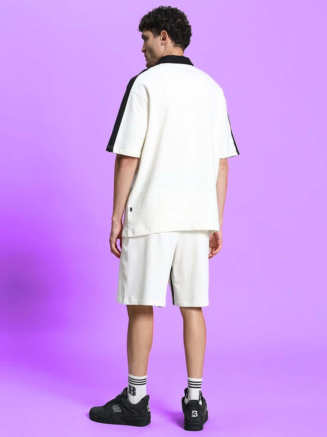 Model wearing Splinter Regular Fit Shorts Off White, showcasing back view against a purple background.