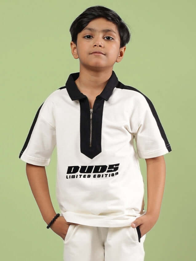 Boy wearing an off white SPLINTER t-shirt by DUDS, designed for both boys and girls, featuring a black collar and accents, against a green backdrop.
