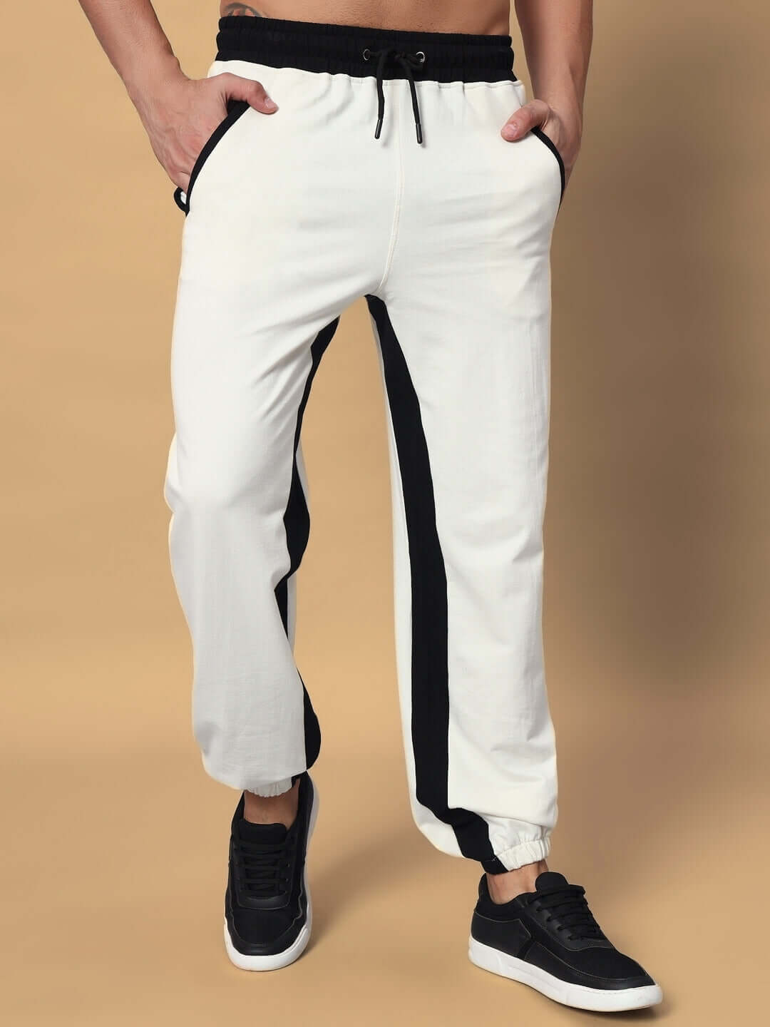 Unisex off-white joggers with black stripes, featuring elasticated waistband and drawstring, made from premium cotton fabric.