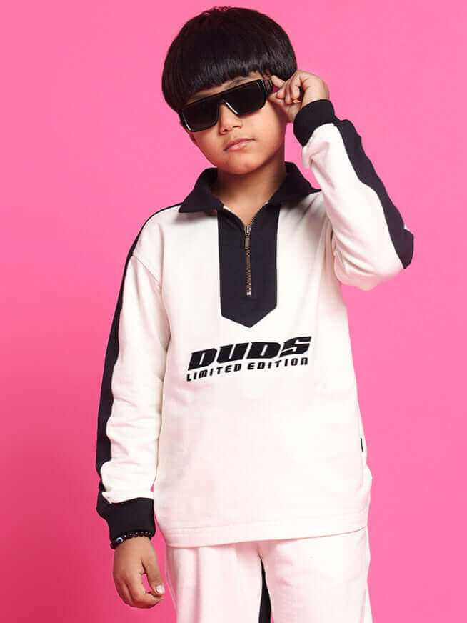 Child wearing off-white oversized co-ord set with black accents and "Duds Limited Edition" text against pink background.