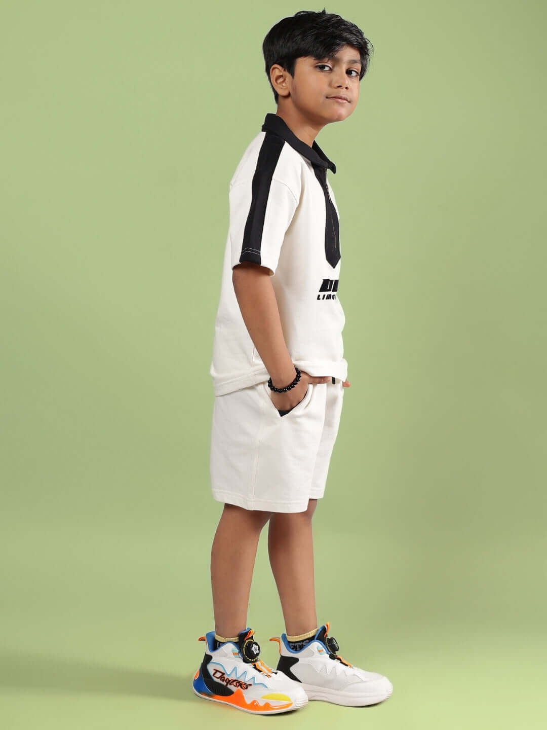 Child wearing Splinter Summer Co-Ord set in off-white, side view with sporty shoes, designed by DUDS for boys and girls.