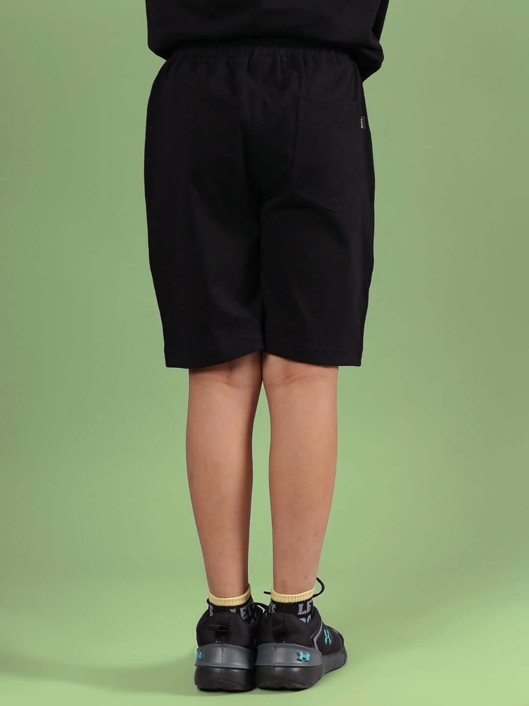 Young person wearing black Squid Game shorts, showcasing back view. Made to order by DUDS, customizable fit available.