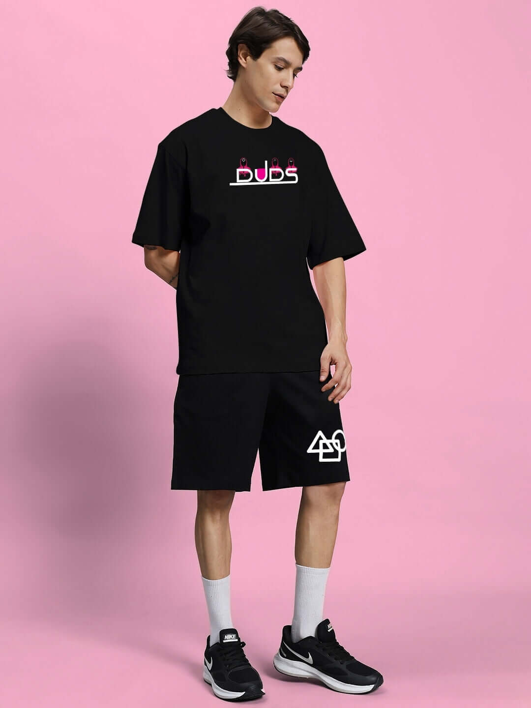 Man wearing SQUID GAME SUMMER CO-ORD SET BLACK against pink background