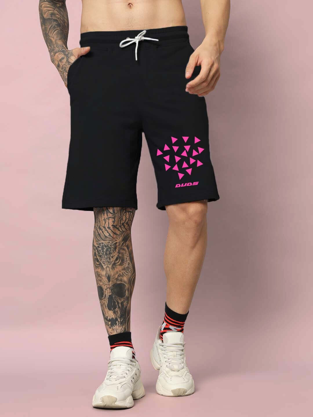Man wearing STAR DUST black shorts with pink geometric design, featuring custom fit options for personalized sizing.
