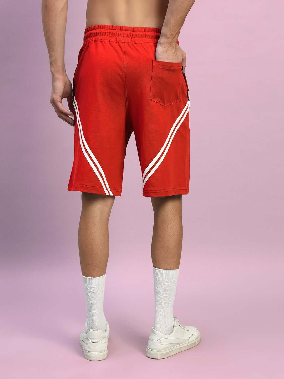 Rear view of person wearing STAR JUMPER regular fit red shorts with white sneakers, highlighting stripe design and pocket detail.
