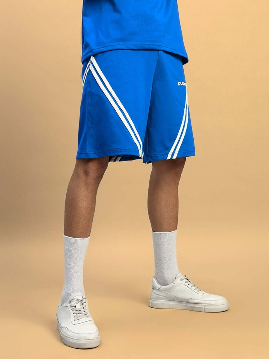 Royal blue STAR JUMPER regular fit shorts with white stripes, worn with white sneakers and socks, showcasing casual sporty style.