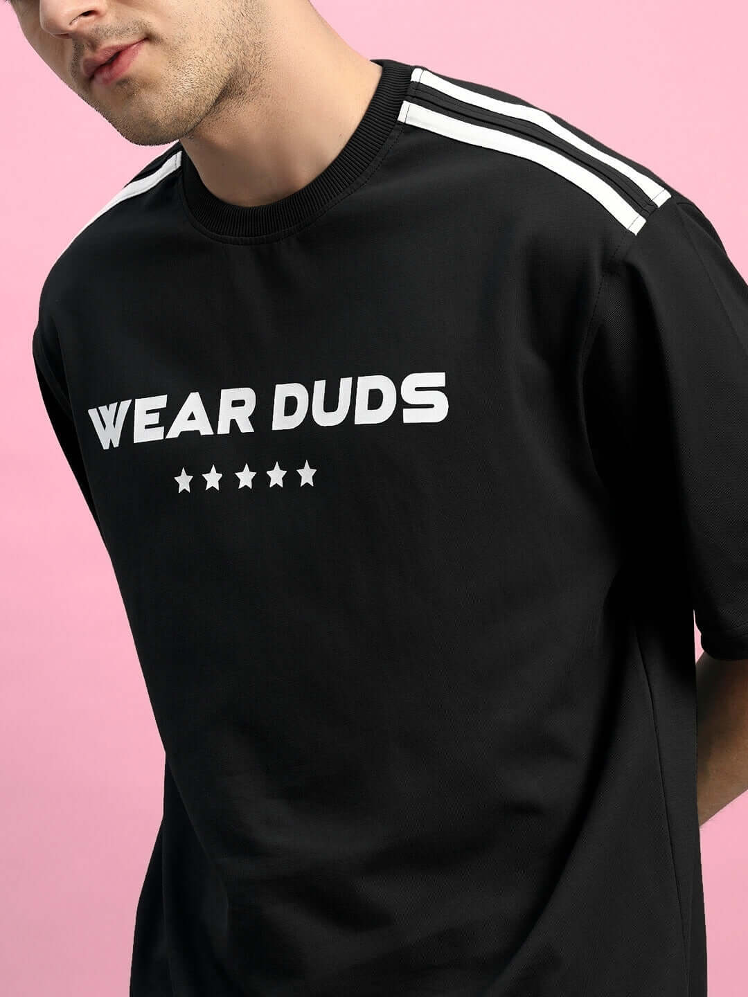 Model wearing STAR JUMPER SUMMER CO-ORD SET BLACK t-shirt with sporty design on a pink background, showcasing stylish streetwear fashion.