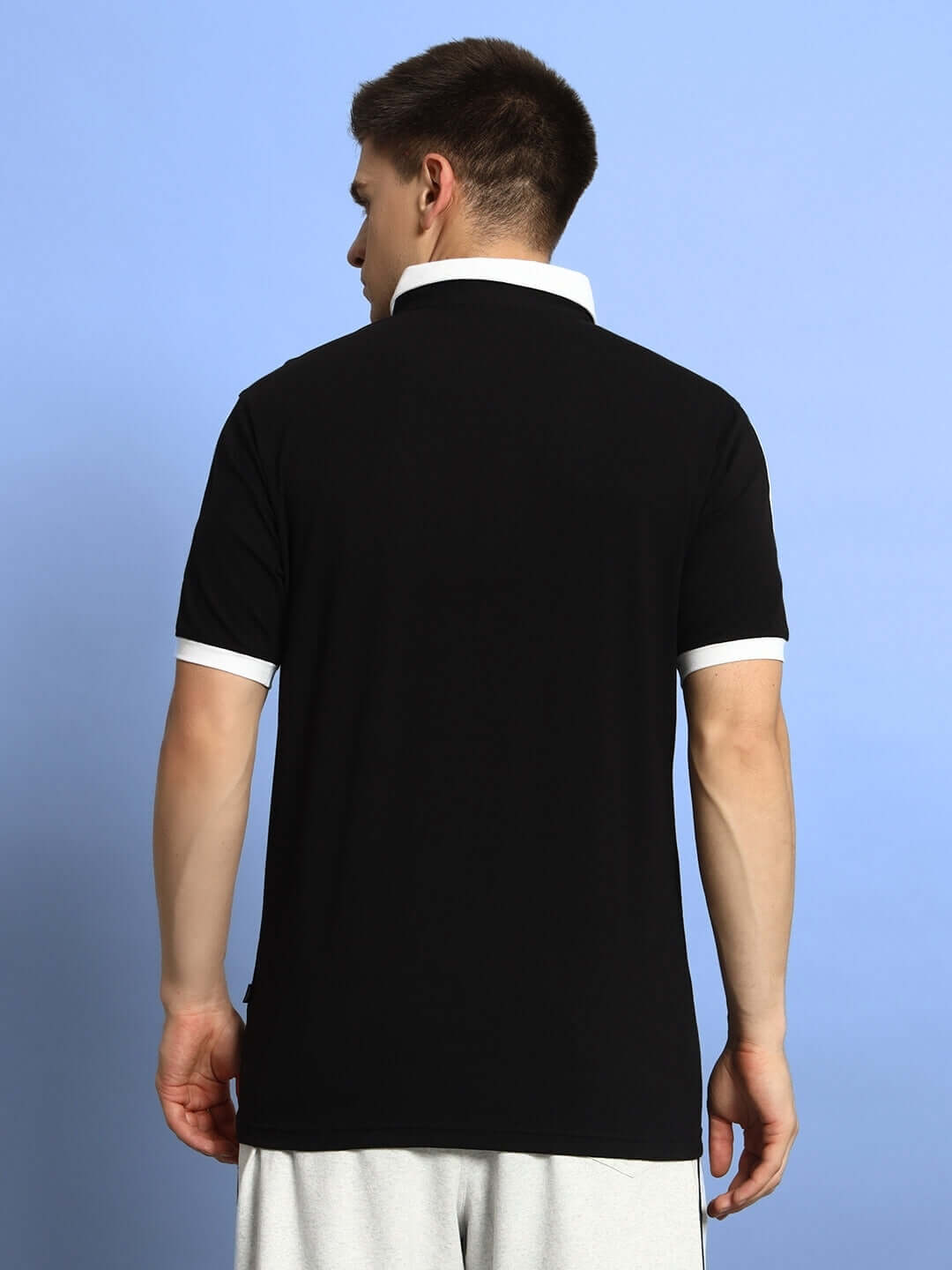 Back view of a model wearing a black Staunch Polo Regular Fit T-shirt with half sleeves, highlighting the premium cotton fabric.
