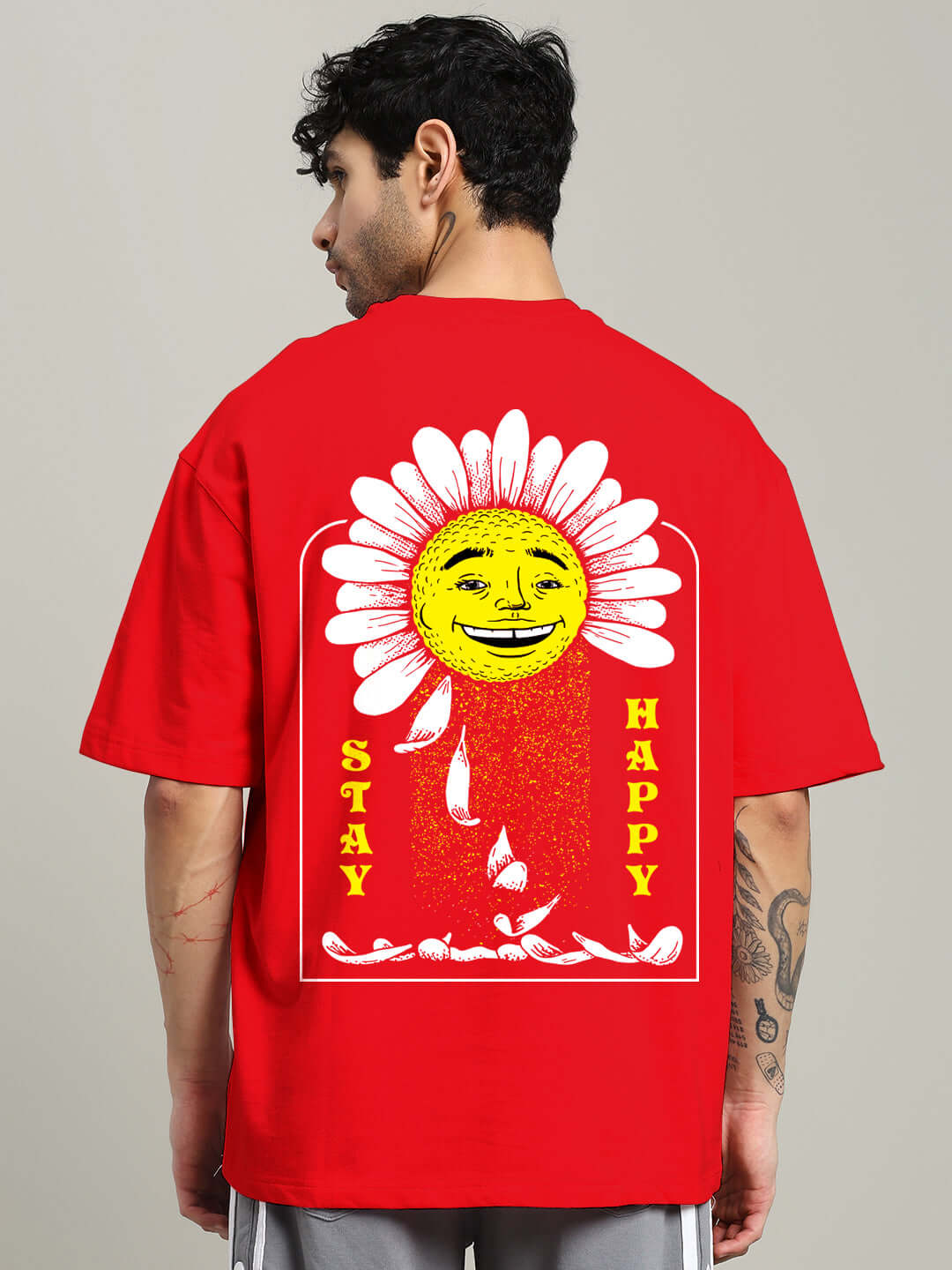 Red oversized t-shirt with 'Stay Happy' print, featuring a smiling sun and daisy graphic. Made from premium cotton blend fabric.