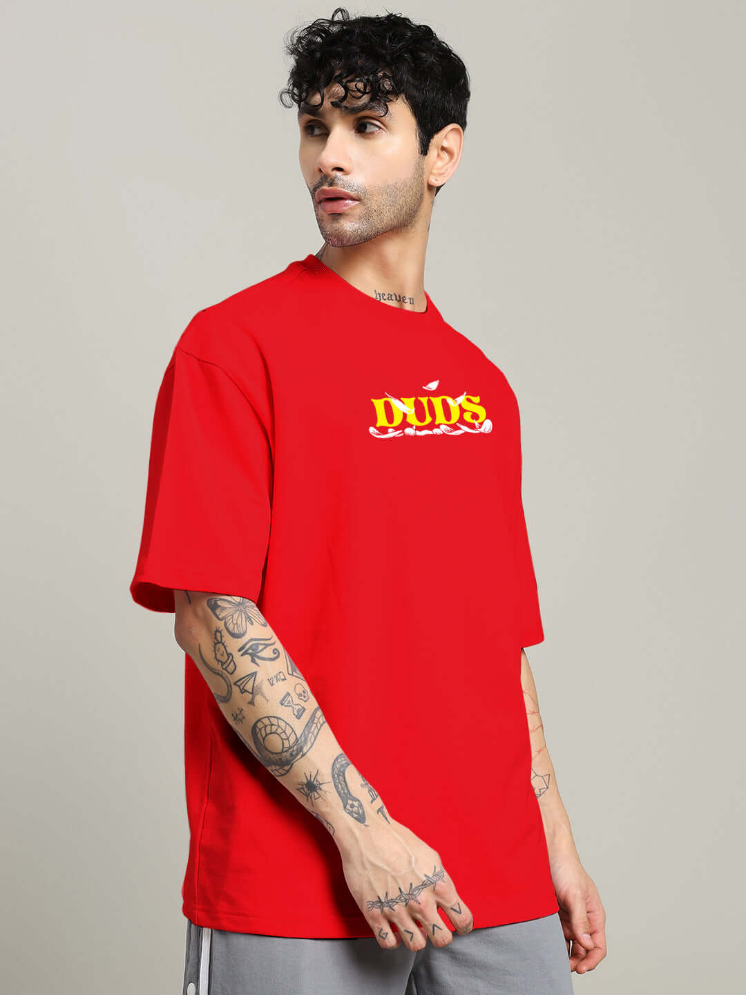 Red oversized t-shirt with graphic print, made from premium cotton blend, worn by a model with tattoos. Ideal for casual style.