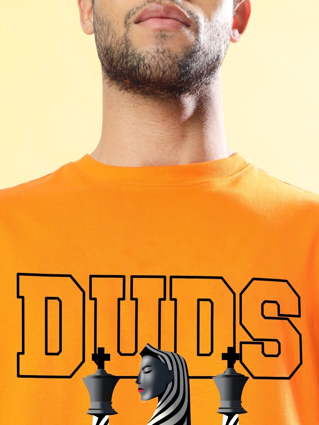 Model wearing STRATEGY RUSE OVER-SIZED T-SHIRT ORANGE with chess print design.