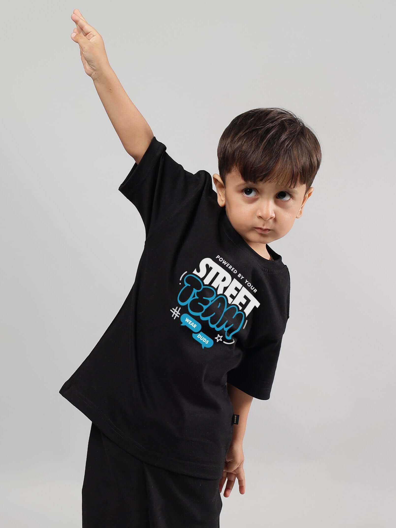Child wearing a black STREET TEAM t-shirt for boys and girls, pose emphasizing the trendy design by DUDS.