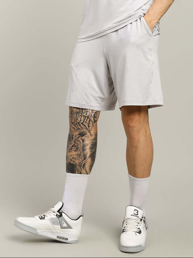 Light grey Strength Freak shorts showcased with sneakers and tattooed leg, highlighting comfort and custom fit options.