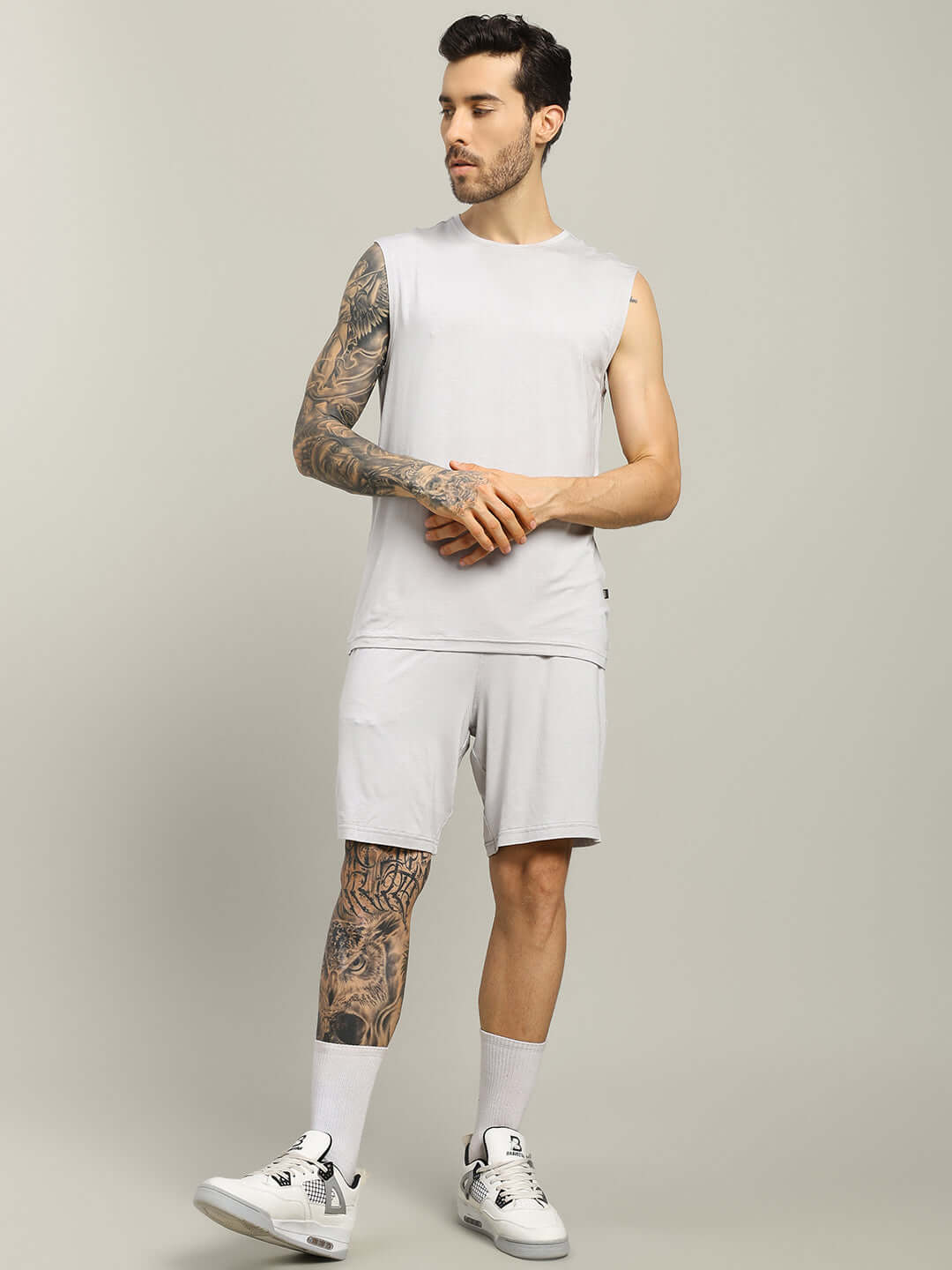 Man wearing light grey Strength Freak shorts and sleeveless top, showcasing casual athletic style. Perfect for customization and comfort.