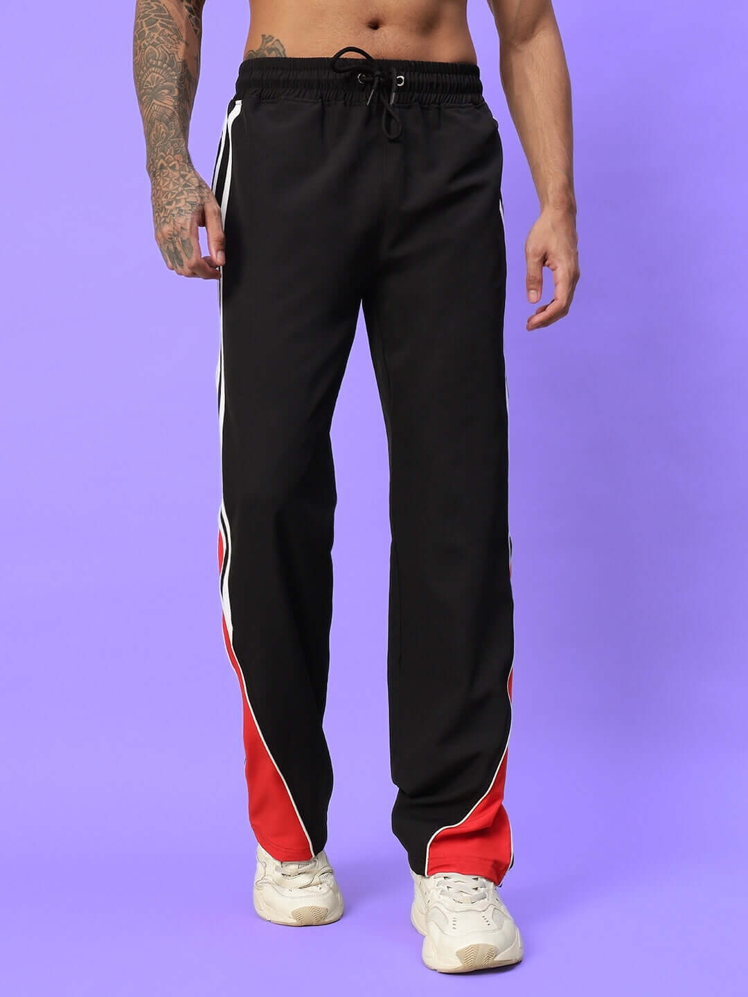 Man wearing black parachute cargo pants with red and white stripes, featuring adjustable drawstring and streetwear style.