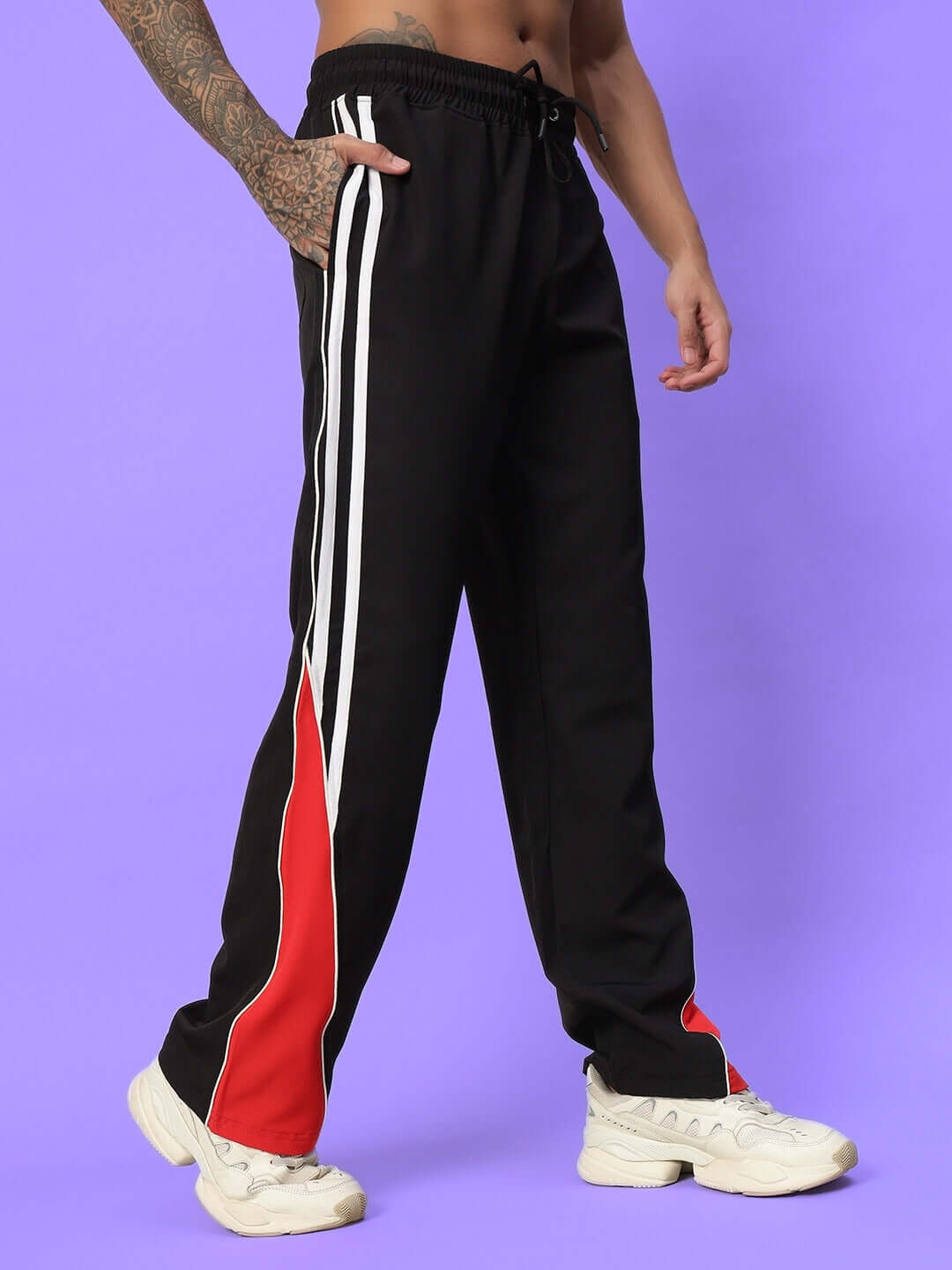 Black string parachute cargo pants with white and red stripe details, shown on a purple background.