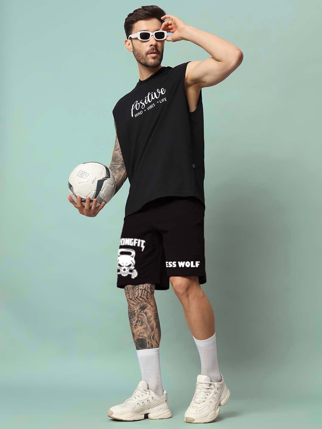 Model wearing STRONGFIT regular fit black shorts, holding a soccer ball, showcasing athletic style and custom fit option.
