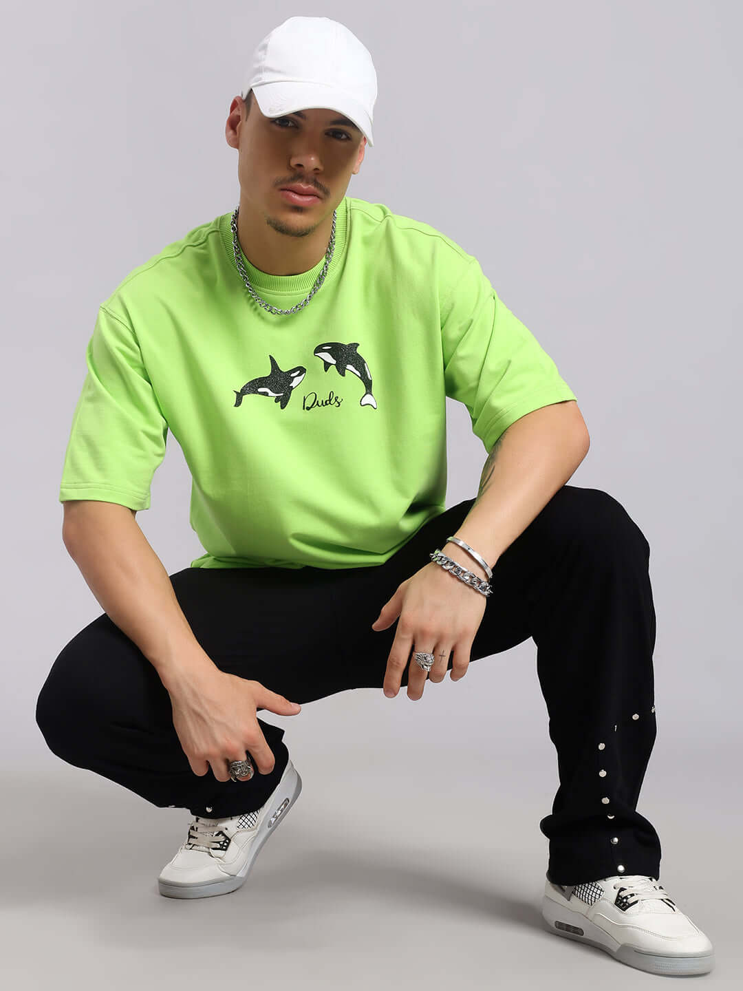 Model wearing Stunner Relaxed Fit Jogger in black, paired with a bright green shirt and white cap.