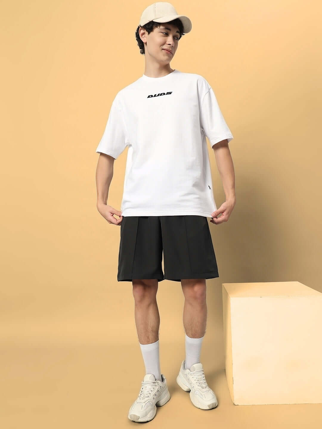 Man wearing dark grey sturdy front plated shorts and white t-shirt, showcasing casual style.