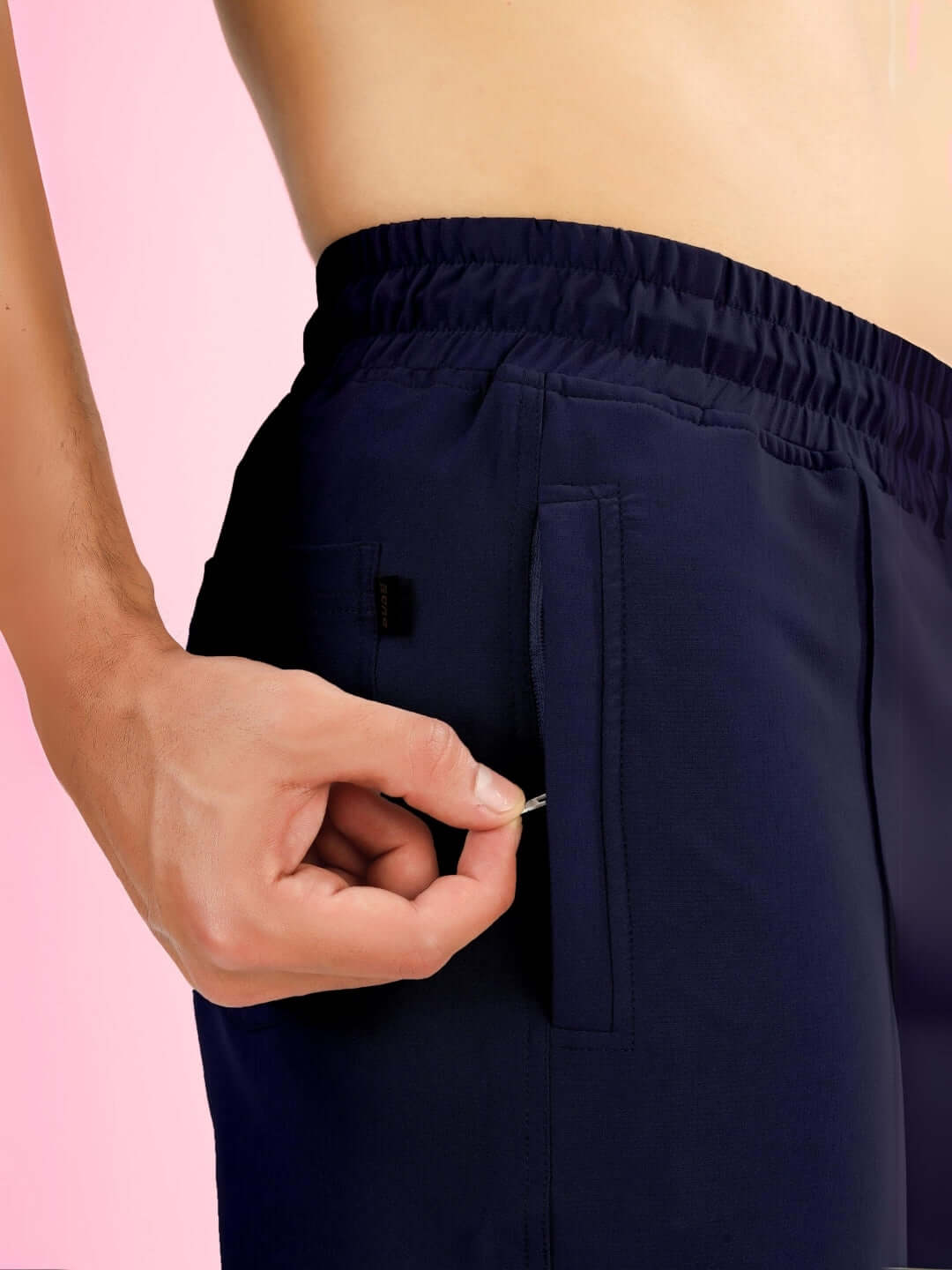 Close-up of a person adjusting the drawstring on navy STURDY FRONT PLATED SHORTS, highlighting the elastic waistband and side pocket detail.
