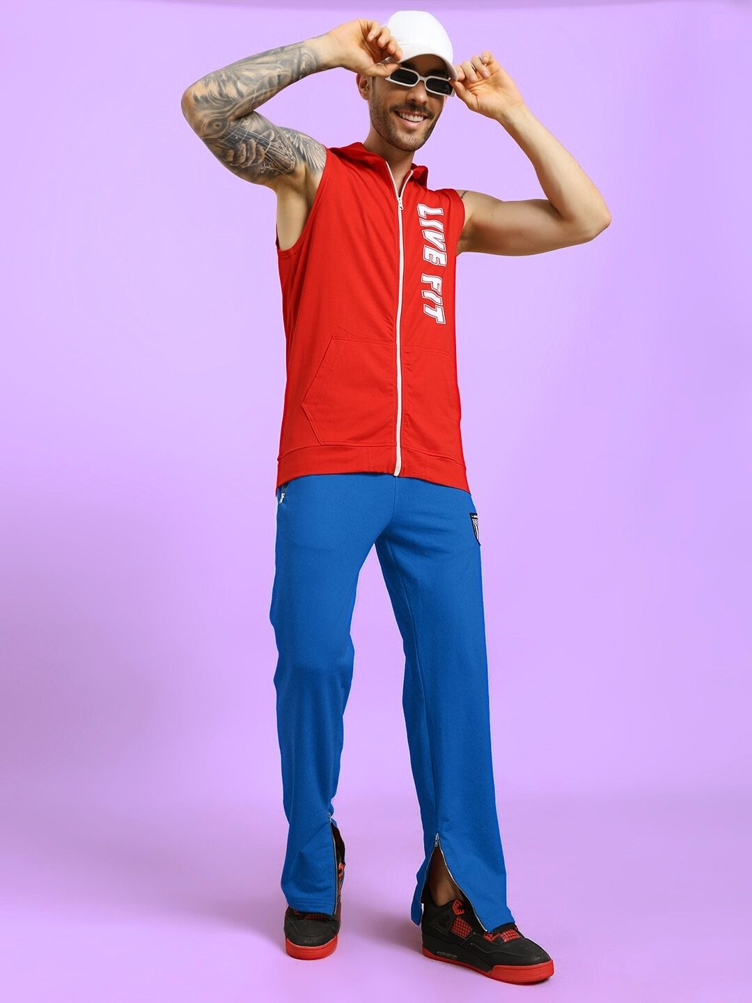 Model wearing ELEGANT RELAXED-FIT JOGGERS BLUE with a red sleeveless hoodie on a light purple background.