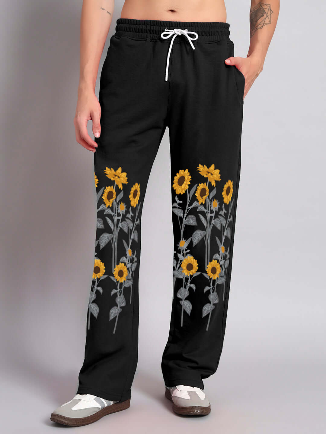 Model wearing black relaxed-fit joggers with sunflower design, featuring drawstring waist and tailored fit by DUDS.