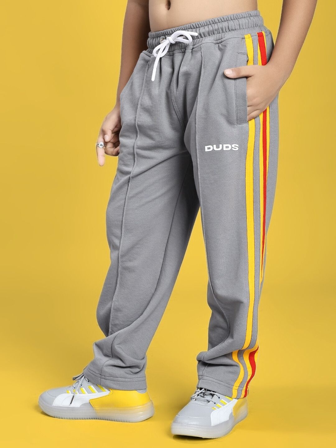 SUNSHINE STRIPE JOGGER FOR BOYS AND GIRLS RED GREY with side pockets and drawstring, worn by a child, featuring red and yellow stripes.